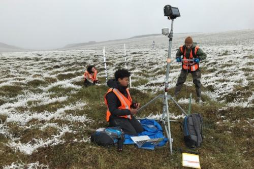 Students conducting fieldwork with devices set up in the grass