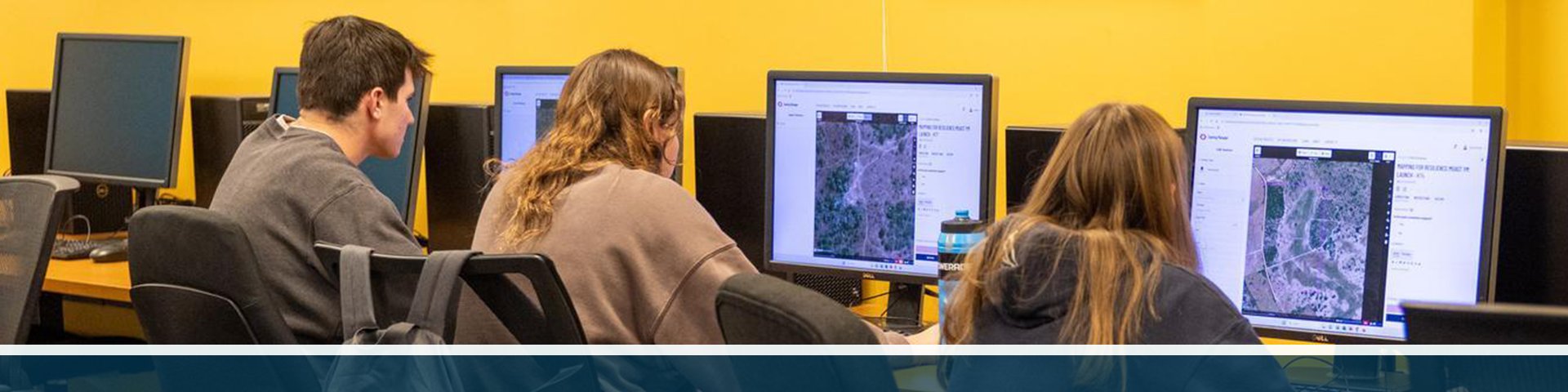 Three students in the GW Spatial Analysis Lab working on computers with GIS software